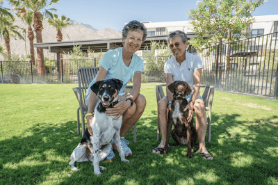 Two residents enjoying time with their dogs in a garden