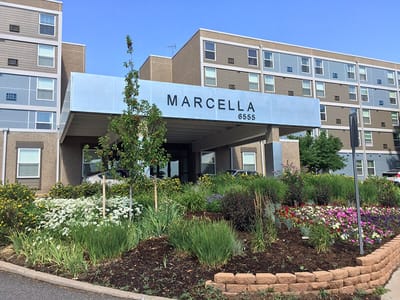 Exterior view of Marcella Manor Apartments entrance and landscaping