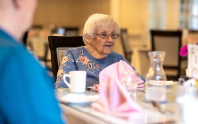 An elderly resident enjoying a meal in a dining room