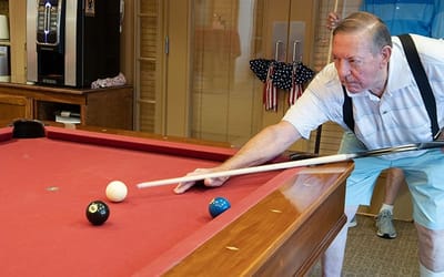 A resident playing billiards in an activity room