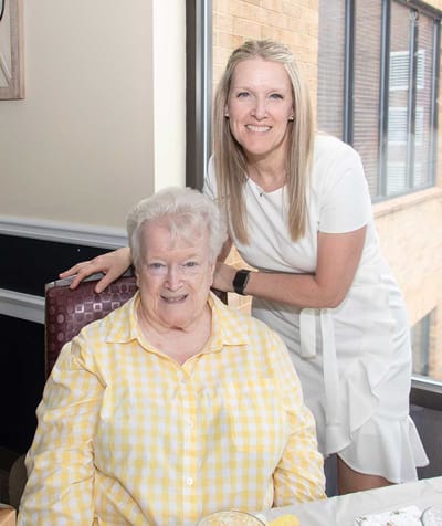 A smiling resident and staff member in a common area