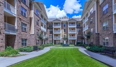 Lush green courtyard with benches and apartment buildings