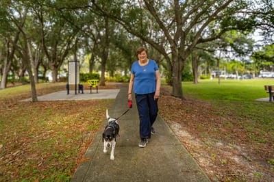 Resident walking a dog in a park-like setting