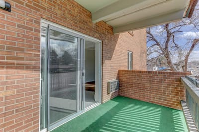 Paramount Garden Apartments, senior living in Lakewood, CO — Balcony with green carpet and brick walls