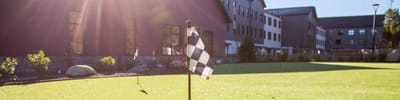 Outdoor putting green with checkered flag in a well-lit area