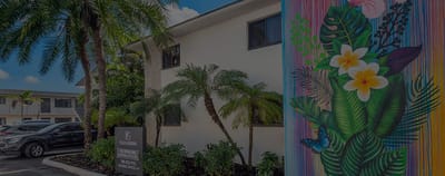 Exterior view of Plaza Gardenia Apartments with tropical plants