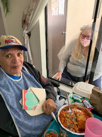 A resident enjoying a meal while a visitor looks in