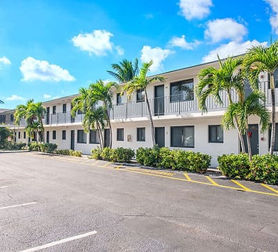 Exterior view of Plaza Gardenia Apartments with landscaping and palm trees