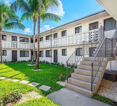 Exterior view of Plaza Gardenia Apartments with gardens and palms