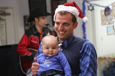 A resident holding a baby and smiling during a holiday celebration