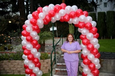 Staff member at a festive outdoor event with balloons