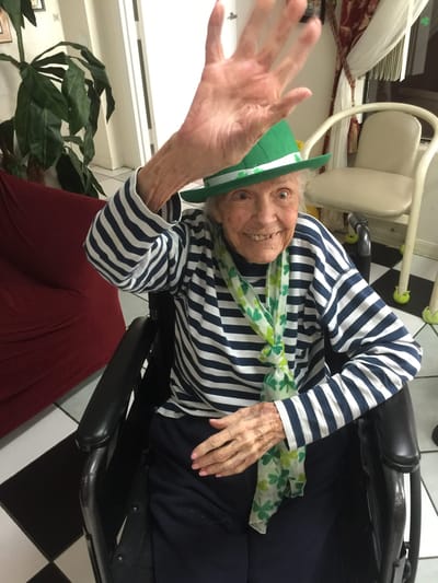 Resident waving with a green hat in a decorated interior