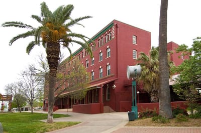 Exterior view of a red brick building with palm trees