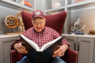 A senior man reading a book in a cozy chair.