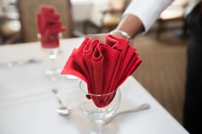 Red napkins elegantly placed in glasses at a dining table.