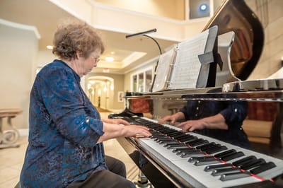 Resident playing piano in a common area