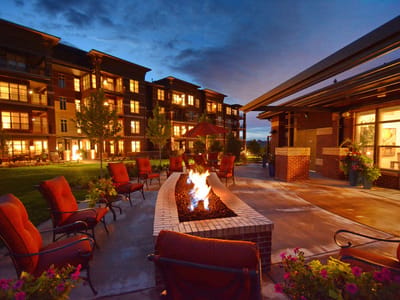 Outdoor seating area with a fire pit and apartment building at dusk