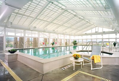 Bright indoor pool area with lounge chairs and flowers