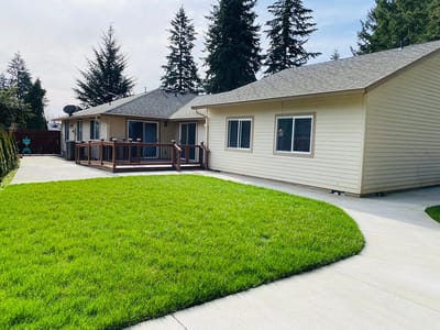 Exterior view of a senior living facility with grass and patio