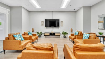 Bright common area with orange chairs and TV