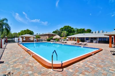 Swimming pool area with seating and buildings in background