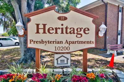 Heritage Presbyterian Apartments sign amidst landscaping.