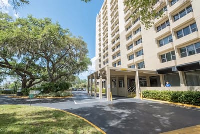 Exterior view of Presbyterian Towers with trees and visitors.