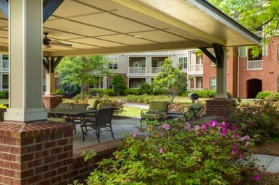 Outdoor seating area with flowers and buildings in background.