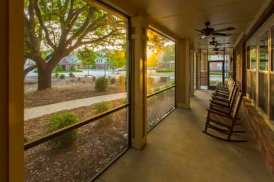 Sunlight filtering through a porch with rocking chairs.