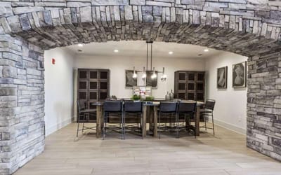 Dining area with stone archway and wooden table.