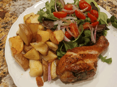 Plate of roasted chicken, potatoes, and salad