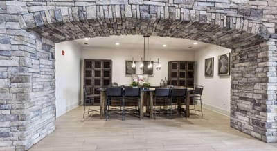Dining area with stone archway and wooden table.