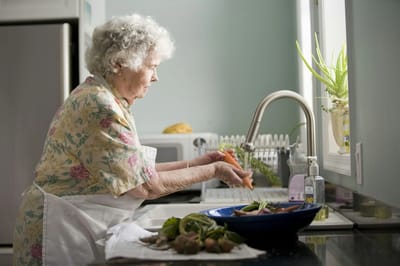 Senior resident washing vegetables in the kitchen.