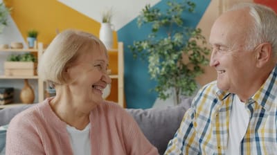 Two seniors enjoying a joyful conversation indoors.