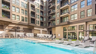 Outdoor pool area with lounge chairs and surrounding buildings.