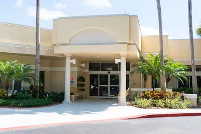Entrance of a retirement living facility with palm trees.