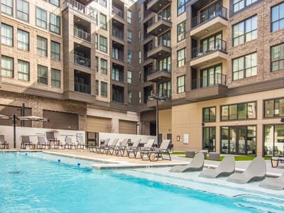 Outdoor pool area with lounge chairs and surrounding building.