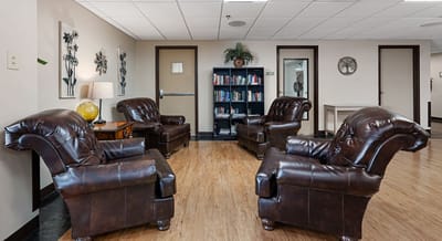 Seating area with leather chairs and bookshelf.