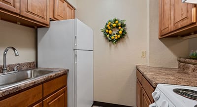 Compact kitchen with wooden cabinets and a lemon wreath.