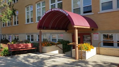 Exterior view of River Park Apartments entrance with flowers