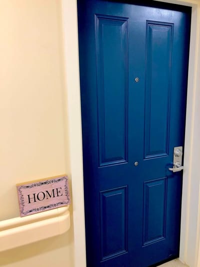 Bright blue door with a 'HOME' sign beside it