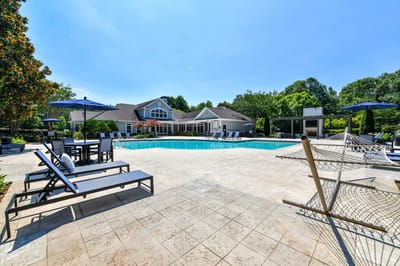 Pool area with seating and hammocks in a sunny setting