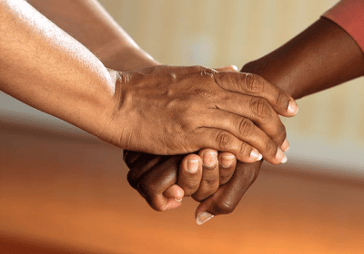 Two hands holding each other in support.