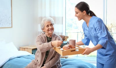 Caregiver serving breakfast to a senior resident.