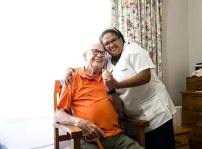 Resident and staff member sharing a joyful moment indoors.