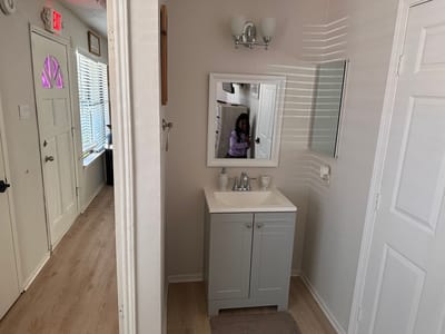 Bright bathroom area with a mirror and sink.