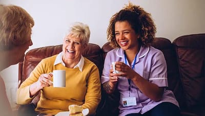 Residents enjoying tea and conversation with caregiver.