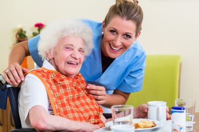 Caregiver assisting an elderly resident with a meal.