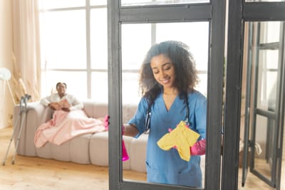 Nurse cleaning while resident relaxes on couch