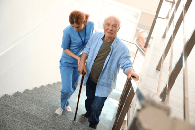 Nurse assisting an elderly man on stairs